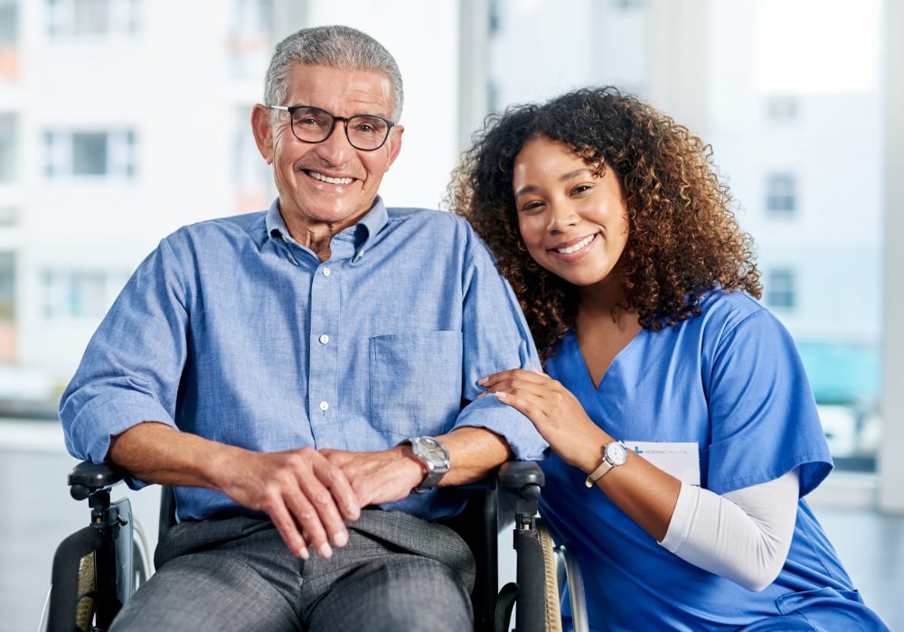 Portrait of a young female nurse posing next to a senior man in a wheelchair at a nursing home
